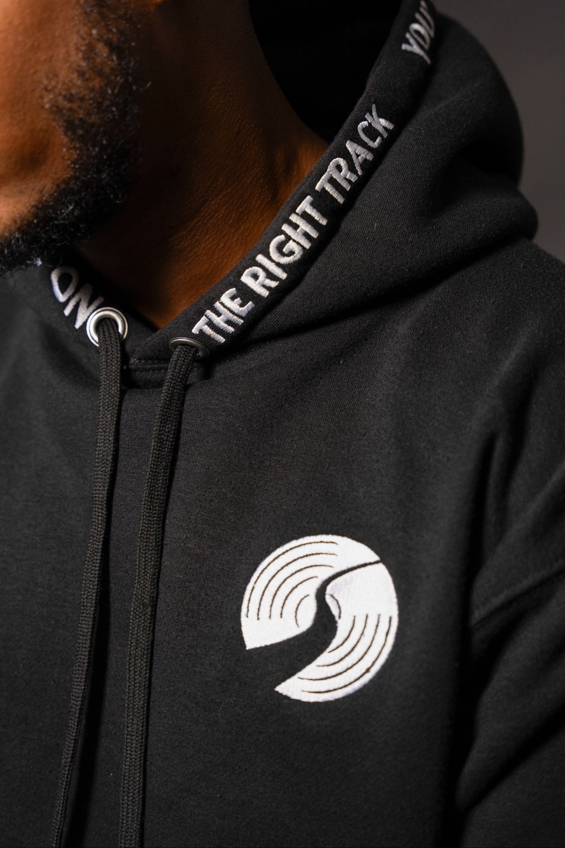 Black hoodie with a logo and text on the hood, worn by DJ Kaptain