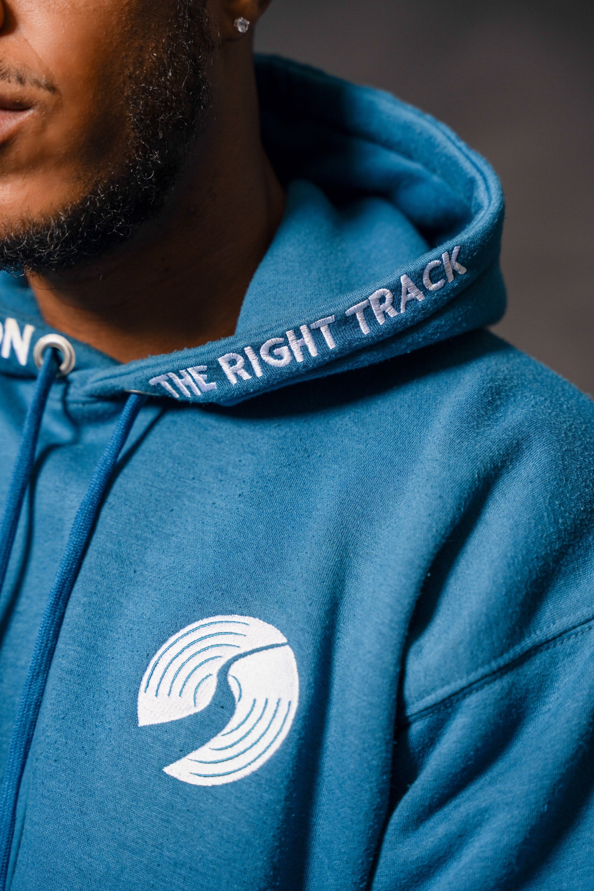 Teal hoodie with 'The Right Track' text and logo on a blurred background